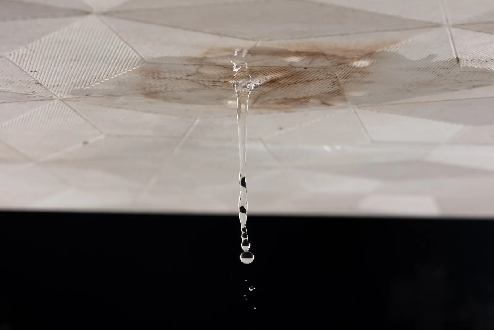Tache d'humidité et goutte d'eau qui tombe d'un plafond