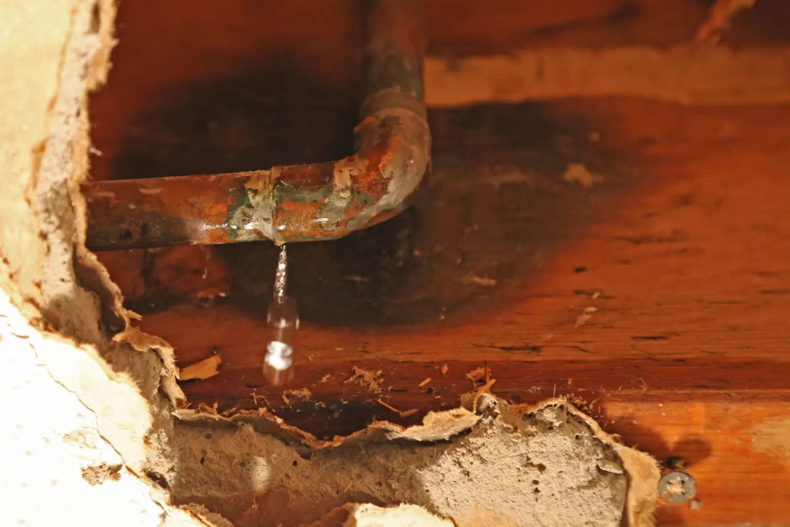 Eau qui s’échappe d’un tuyau en cuivre dans un mur ouvert