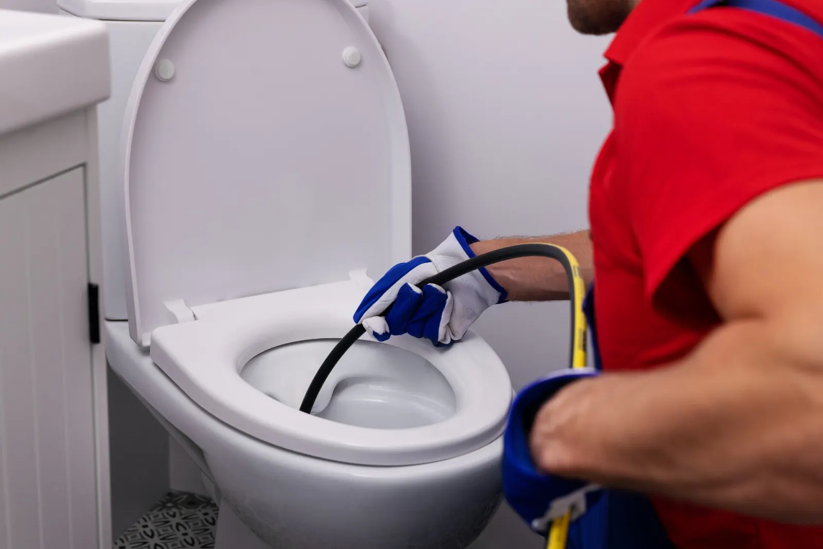 Plombier qui introduit un câble dans la cuvette d'un WC