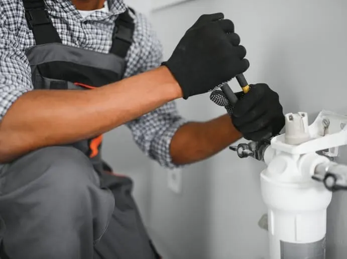 Plombier qui raccorde un filtre à eau avec une pince