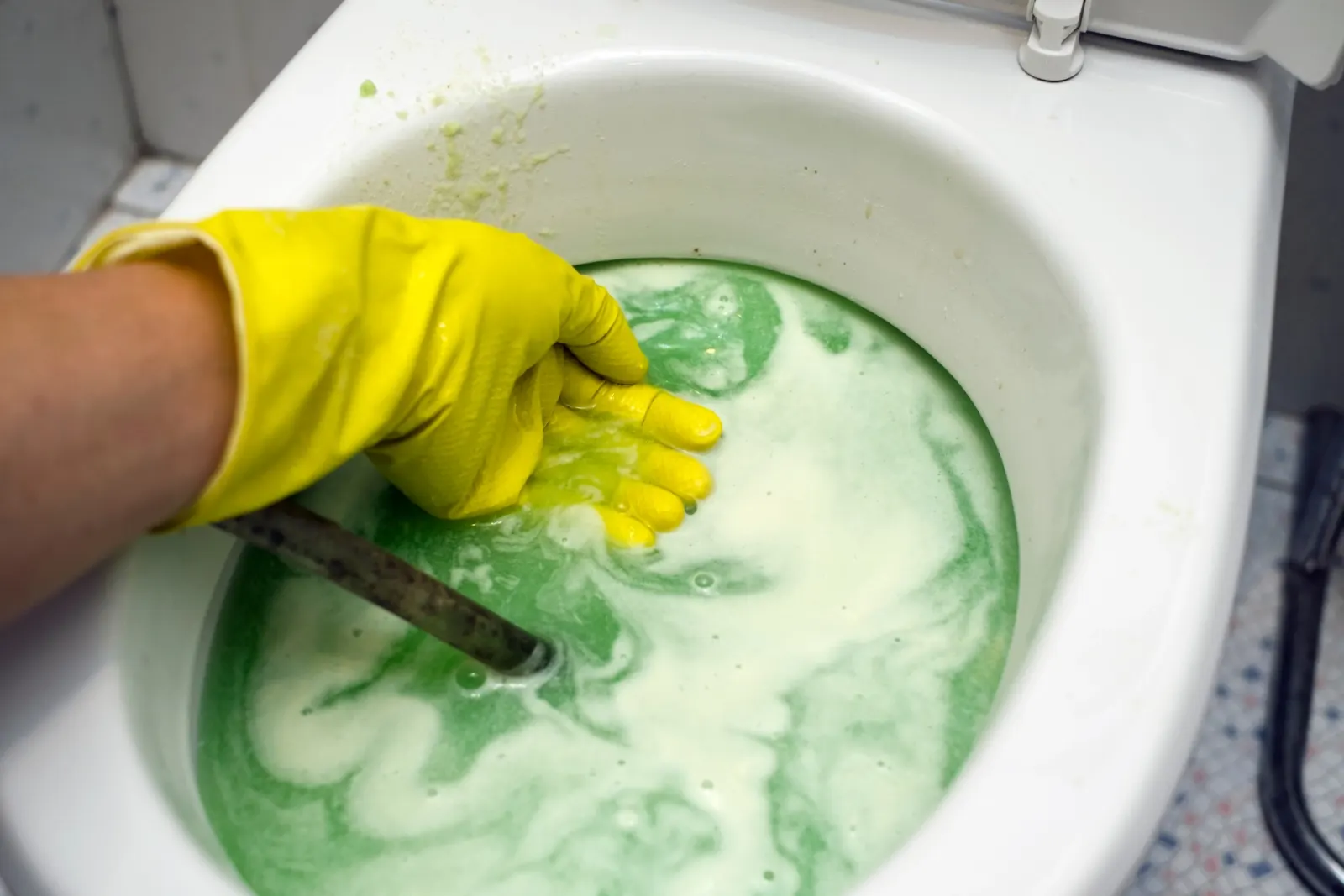 Cuvette d'un WC nettoyée avec un gant jaune