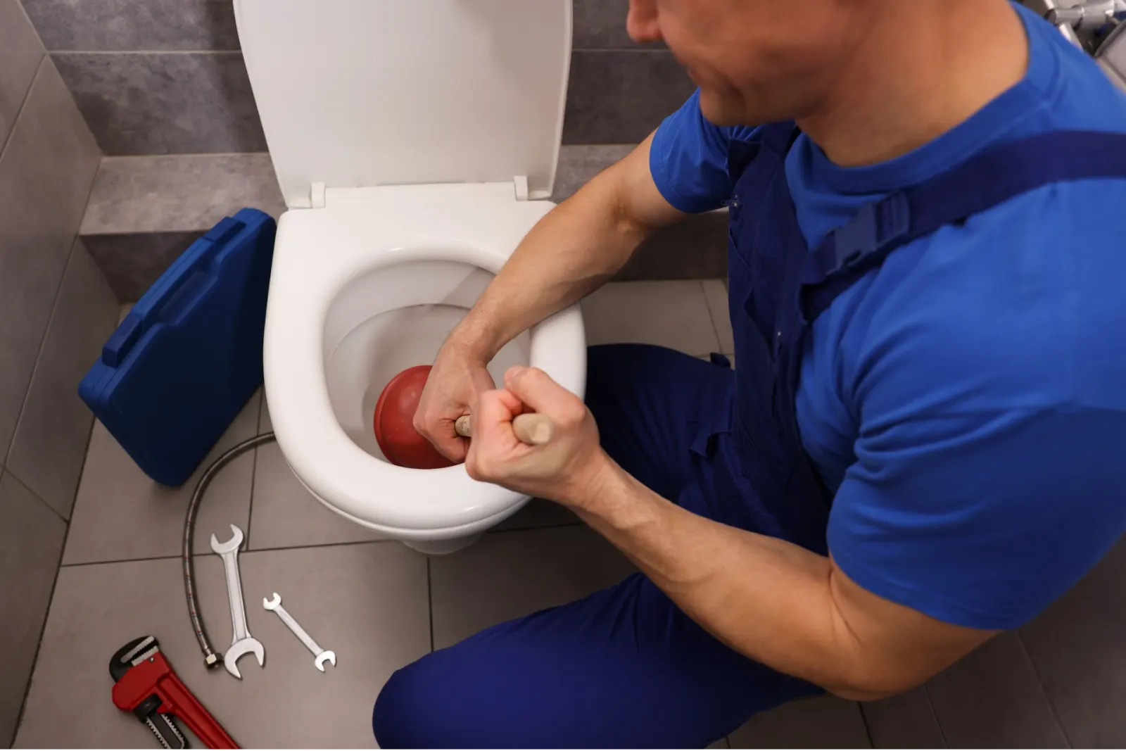 Plombier qui débouche un WC avec une ventouse