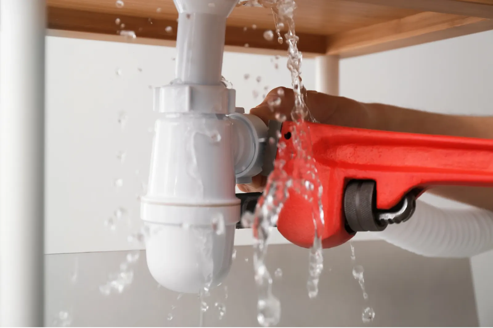 Siphon d'évier qui fuit, serré avec une clé à tube rouge