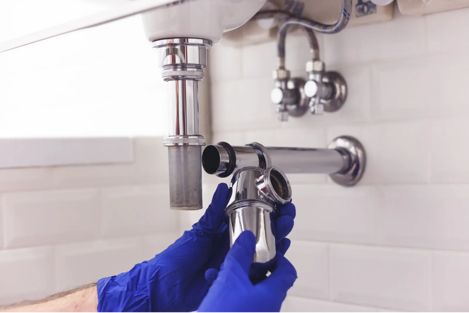 Démontage d’un siphon chromé sous un lavabo